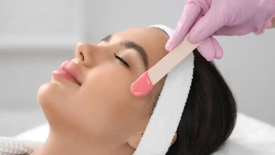 Woman receiving facial waxing treatment at a spa.